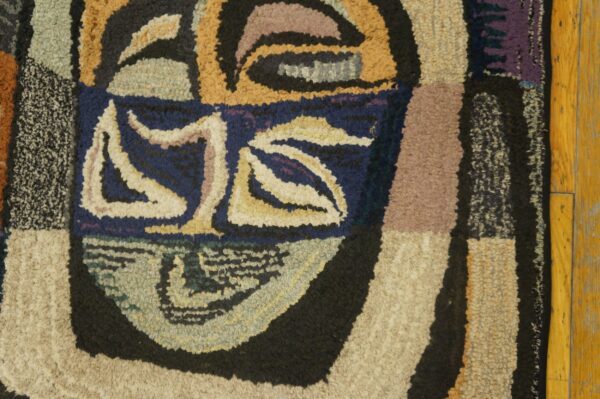 Close-up of a colorful, abstract, hooked rug design resembling a face, by rugs on net. By rugs on net