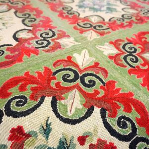Close-up of a traditional rug featuring red and black scrollwork over green and cream fields, by Rugs On Net