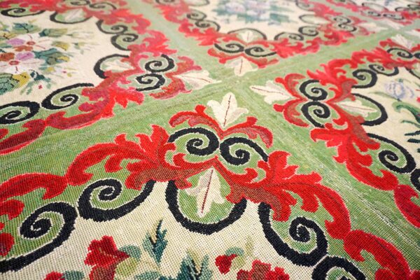 Close-up of a traditional rug featuring red and black scrollwork over green and cream fields, by rugs on net