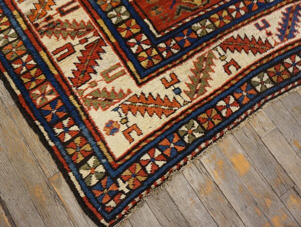 Close-up of a richly patterned area rug border featuring geometric motifs in red, blue, and cream, by rugs on net