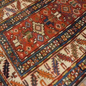 Close-up of a richly colored antique rug with geometric patterns and a dominant red field, by Rugs On Net
