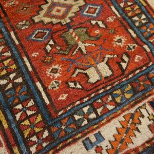 Close-up of a vibrant, richly colored antique rug with geometric patterns by Rugs On Net