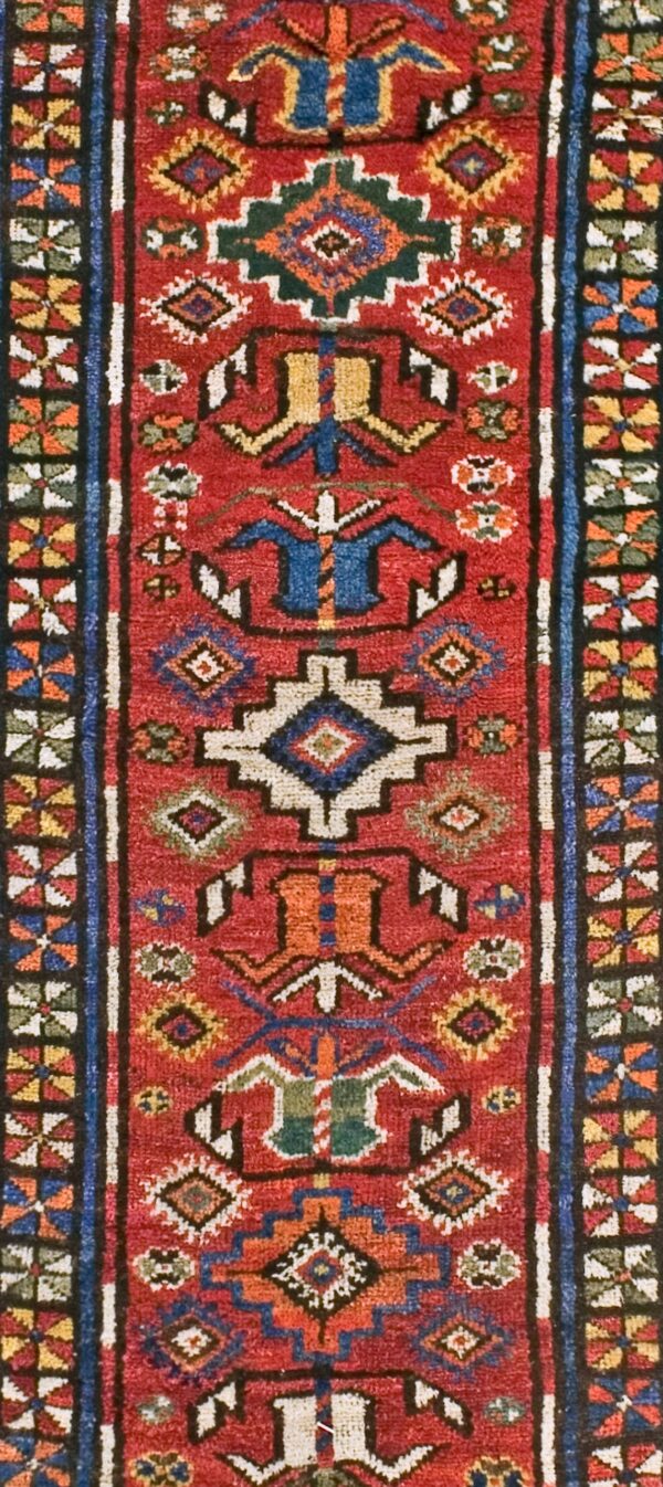 Close-up of a vibrant red tribal rug with geometric motifs in blue, white, and gold by rugs on net