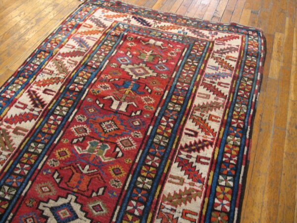 Close-up of a vibrant, antique caucasian rug with geometric patterns on a wooden floor by rugs on net