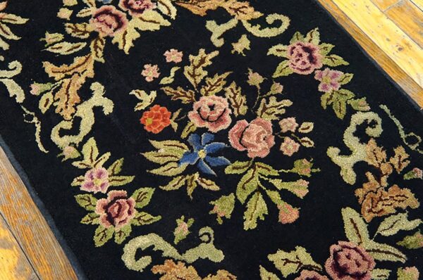 Close-up of a black floral rug with pink and blue flowers by rugs on net