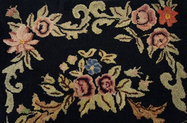 Close-up of a black rug featuring pink and orange floral motifs with green-gold leaves, by rugs on net