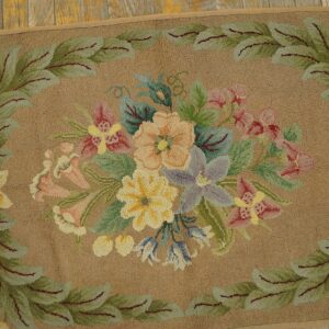 A close-up of a floral hooked rug with pastel flowers on a tan background, bordered by green leaves, by Rugs On Net. by Rugs On Net