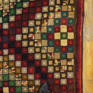 Close-up of a multicolored square-patterned rug next to yellowed wood flooring, by Rugs On Net. by Rugs On Net