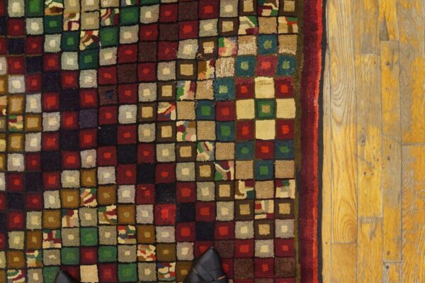 Close-up of a multicolored square-patterned rug next to yellowed wood flooring, by rugs on net. By rugs on net