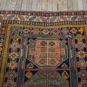 Close-up of a colorful antique rug with geometric patterns on a wooden floor by Rugs On Net