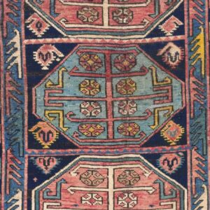 Detail of a geometric Caucasian rug with blue and pink medallions by Rugs On Net