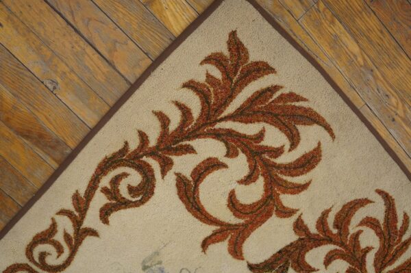 Close-up corner view of an ivory rug with burnt orange scrollwork pattern on rustic wood floor by rugs on net