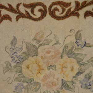 Close-up of a floral rug design featuring soft yellow and pink roses with blue accents on a cream background, framed by an ornate brown border, by Rugs On Net