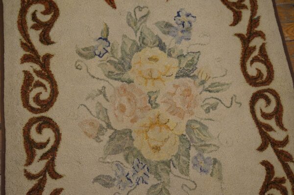 Close-up of a floral hooked rug with yellow and pink roses and blue accents, framed by brown scrollwork, by rugs on net