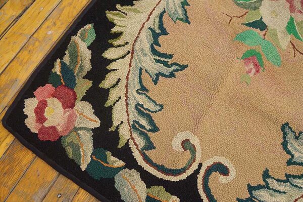 Close-up of a floral hooked rug with pink and green elements on a tan field and black border, by rugs on net