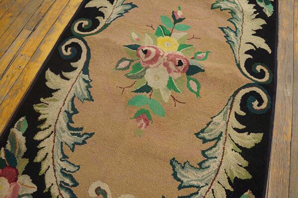 Close-up of a hooked rug featuring a central bouquet of pink and yellow roses against a tan ground, framed by black borders and scrolling foliage designs, by rugs on net