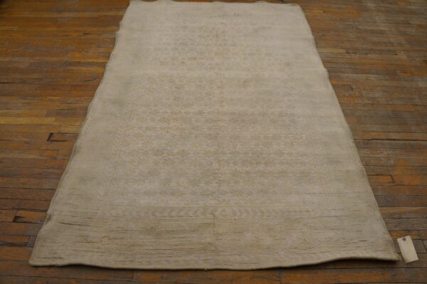 A light beige, subtly patterned rug lying on a rustic wooden floor by rugs on net. By rugs on net