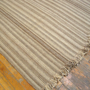 Close-up of a striped natural fiber rug corner on wood floor by Rugs On Net