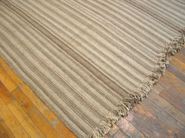 Close-up of a striped natural fiber rug corner on wood floor by rugs on net