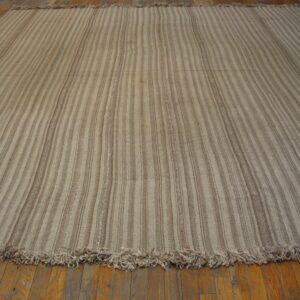 Close-up of a striped beige and brown Kilim rug laid on wood flooring by Rugs On Net. by Rugs On Net