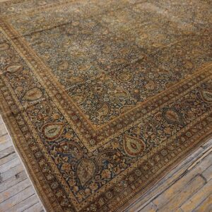 Close-up corner view of a dark blue and gold paisley patterned Persian rug on distressed wood flooring by Rugs On Net