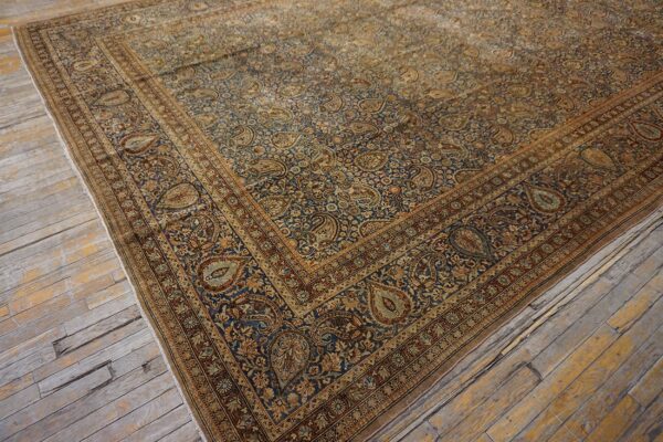 Close-up corner view of a dark blue and gold paisley patterned persian rug on distressed wood flooring by rugs on net