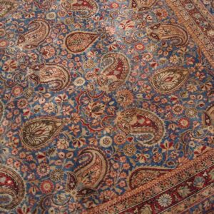 Close-up of a blue field rug with repeating paisley motifs and floral elements, by Rugs On Net