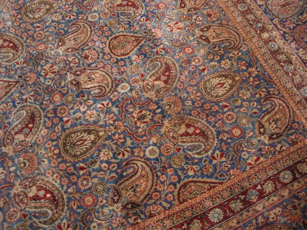 Close-up of a blue field rug with repeating paisley motifs and floral elements, by rugs on net