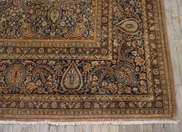 Close-up corner detail of a blue persian rug with intricate paisley and floral borders by rugs on net. By rugs on net