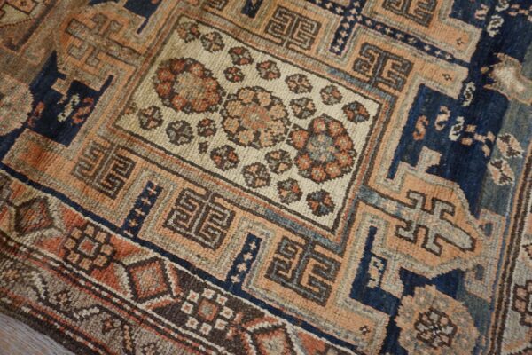 Close-up of an antique rug featuring geometric and floral motifs in muted orange, blue, and cream tones, by rugs on net
