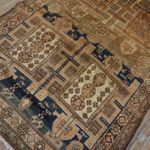 Close-up of an antique rug with geometric patterns in muted blues, browns, and peaches on a distressed wood floor by Rugs On Net. by Rugs On Net