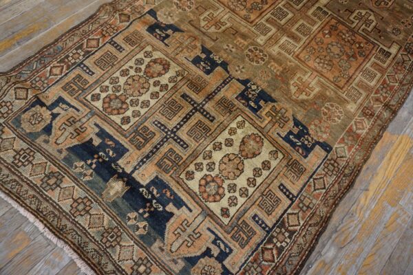 Close-up of an antique rug with geometric patterns in muted blues, browns, and peaches on a distressed wood floor by rugs on net. By rugs on net