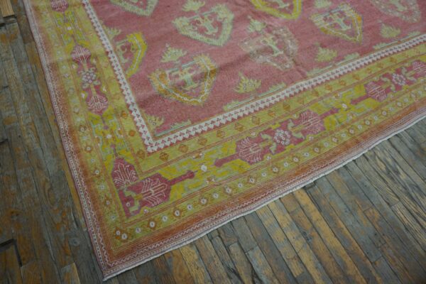 Close-up of the corner of a pink and yellow vintage rug on a wooden floor by rugs on net