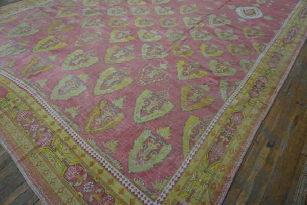 Close-up view of a pink and yellow patterned rug featuring repeating shield motifs, by rugs on net. By rugs on net