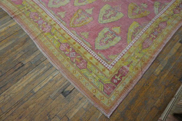 Close-up of a pink and yellow patterned rug corner on wooden floor by rugs on net