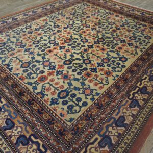 Close-up of a vintage area rug featuring cream field with blue and coral floral motifs and intricate borders, by Rugs On Net