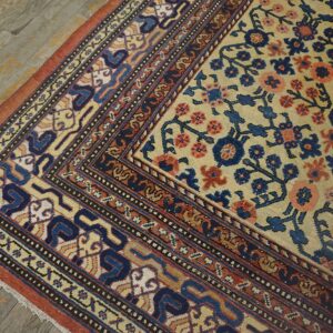 Close-up corner detail of an antique floral rug featuring beige, blue, and coral tones on a distressed wooden floor by Rugs On Net