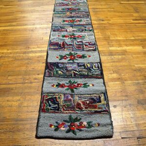 A long, narrow hooked rug with repeating floral and abstract panels on a wooden floor by Rugs On Net. by Rugs On Net