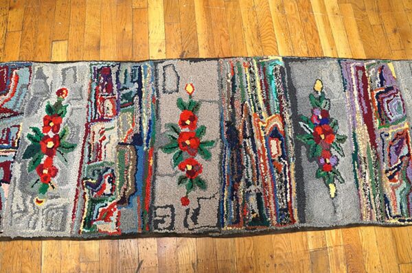 Long, colorful hooked rug with floral elements on a wooden floor by rugs on net