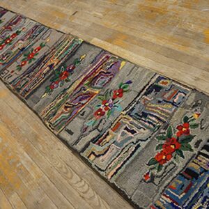A long, narrow rag rug with gray panels interspersed with colorful abstract patterns and red floral motifs, laid on a light wooden floor by Rugs On Net. by Rugs On Net