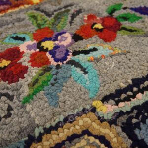 Close-up of a colorful floral pattern on a gray hooked rug by Rugs On Net