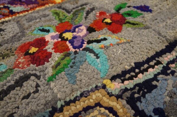 Close-up of a colorful floral pattern on a gray hooked rug by rugs on net