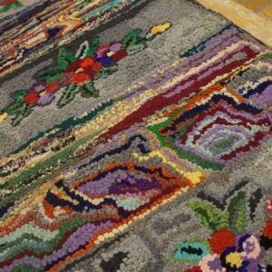 Close-up of a colorful hooked rag rug with floral accents on a gray background, by Rugs On Net