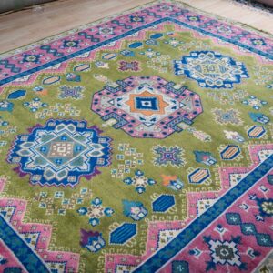 Green and fuchsia Kazak hand-knotted rug, angled view showing medallions