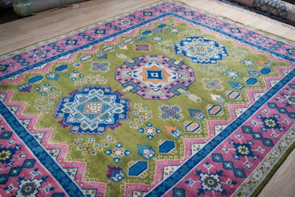 Ava kazak light green hand knotted wool rug 7 Green and fuchsia kazak hand-knotted rug, angled view showing medallions