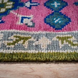 Green and fuchsia Kazak rug border close-up