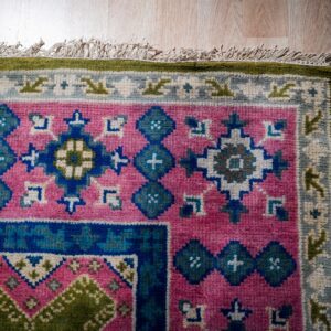 Green and fuchsia Kazak rug corner detail