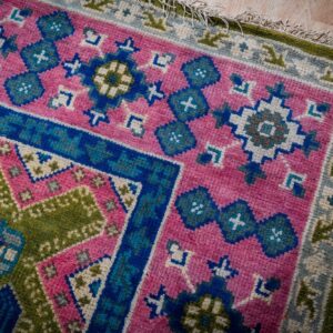 Green and fuchsia Kazak rug corner and fringe detail