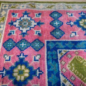 Green and fuchsia Kazak rug corner pattern detail