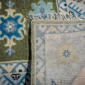 Light green beige Kazak rug corner folded showing the back